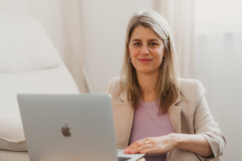 Die Webdesignerin Finja sitzt an ihrem Laptop und lächelt in die Kamera.