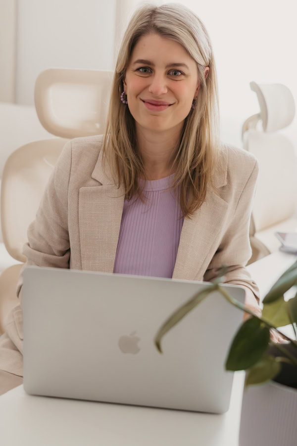 Finja Wolkenstein sitzt an ihrem Schreibtisch hinter ihrem Laptop und lächelt in die Kamera.