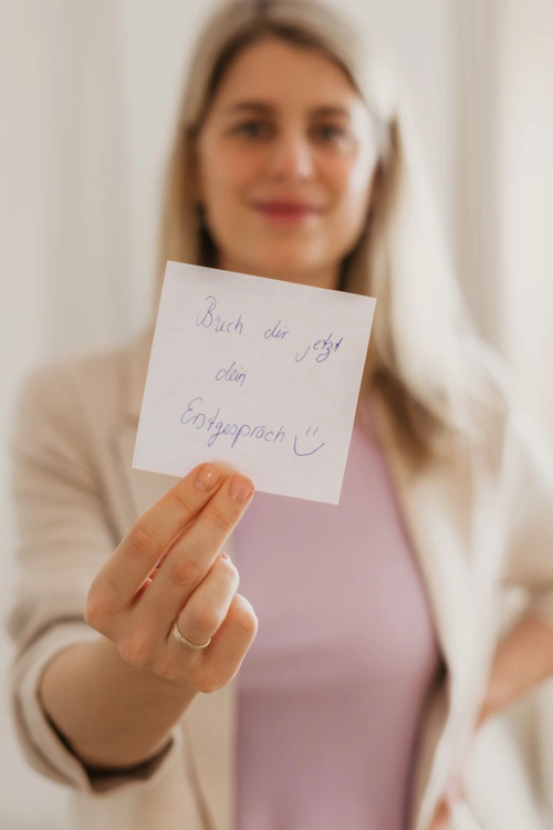 Die Webdesignerin Finja Wolkenstein hält einen Zettel in die Kamera: Buch dir dein Erstgespräch.